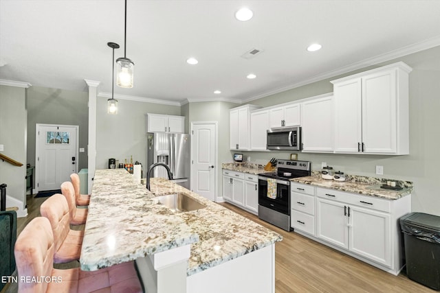 kitchen with sink, decorative light fixtures, appliances with stainless steel finishes, an island with sink, and white cabinets