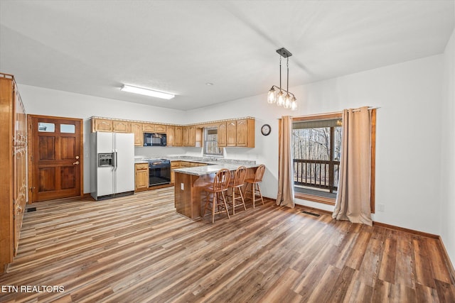 kitchen featuring a breakfast bar, range, kitchen peninsula, white fridge with ice dispenser, and pendant lighting