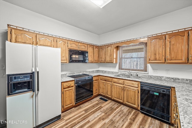 kitchen with sink, black appliances, and light wood-type flooring