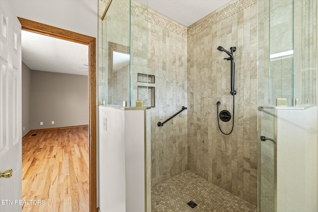 bathroom featuring wood-type flooring and a tile shower