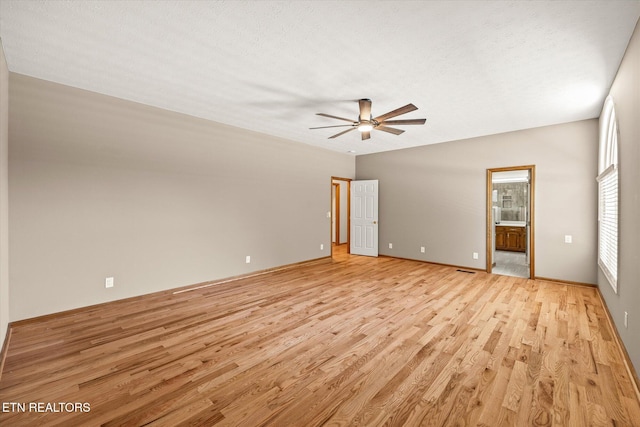 unfurnished bedroom featuring ceiling fan, ensuite bath, light hardwood / wood-style flooring, and a textured ceiling