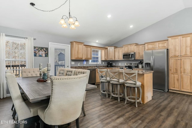 kitchen featuring dark hardwood / wood-style flooring, hanging light fixtures, a kitchen island, and appliances with stainless steel finishes