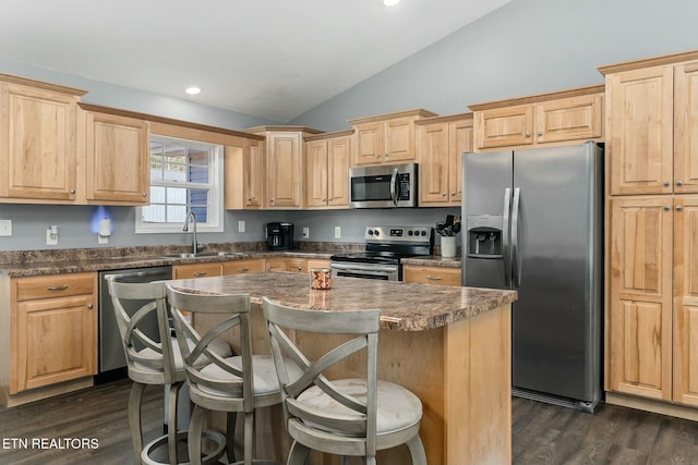 kitchen featuring lofted ceiling, sink, a breakfast bar area, appliances with stainless steel finishes, and a kitchen island