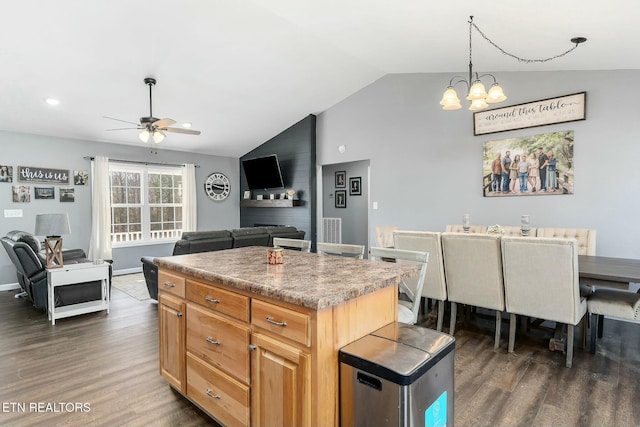 kitchen featuring ceiling fan with notable chandelier, dark hardwood / wood-style floors, a kitchen island, decorative light fixtures, and vaulted ceiling