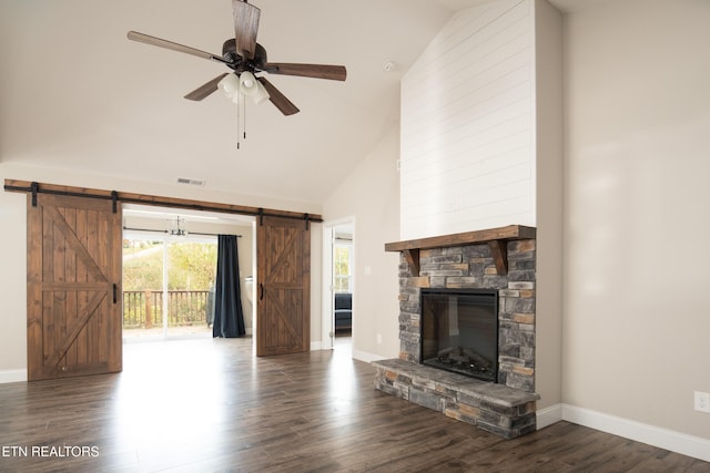 unfurnished living room featuring ceiling fan, high vaulted ceiling, dark hardwood / wood-style floors, a stone fireplace, and a barn door