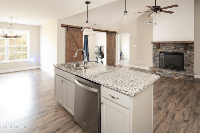 kitchen featuring white cabinetry, dishwasher, sink, hanging light fixtures, and a barn door