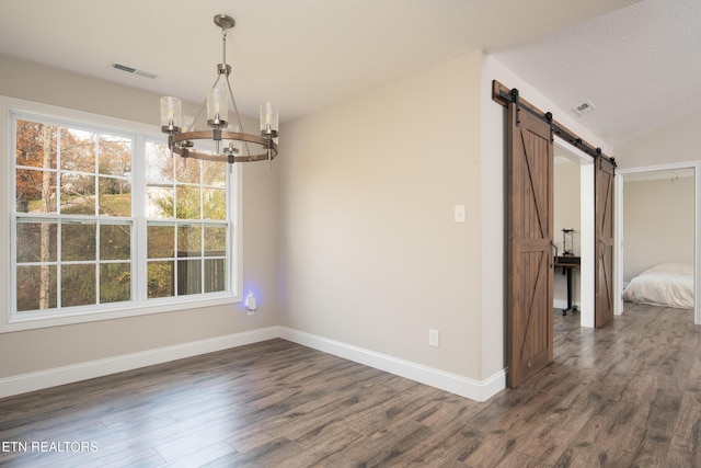 unfurnished dining area featuring dark hardwood / wood-style floors, vaulted ceiling, a barn door, and a chandelier