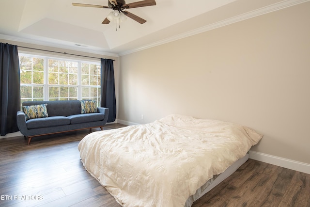 bedroom featuring crown molding, a tray ceiling, dark wood-type flooring, and ceiling fan