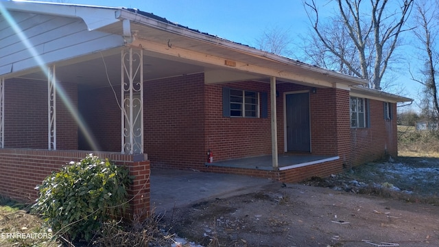 view of side of home with driveway, an attached carport, a patio, and brick siding