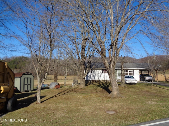 view of front of property with a carport, a front yard, and a storage shed