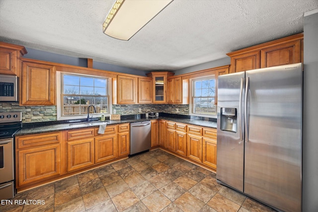 kitchen with dark stone countertops, appliances with stainless steel finishes, sink, and backsplash