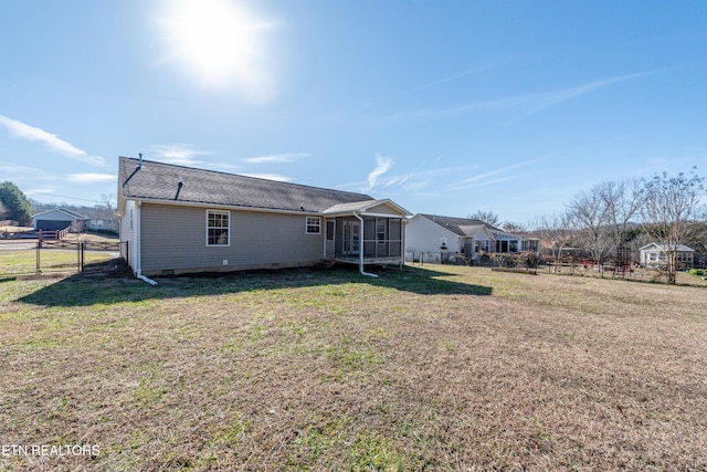 rear view of house with a yard and a sunroom