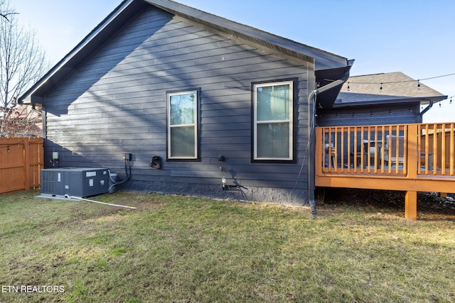 rear view of house featuring central AC, a deck, and a lawn