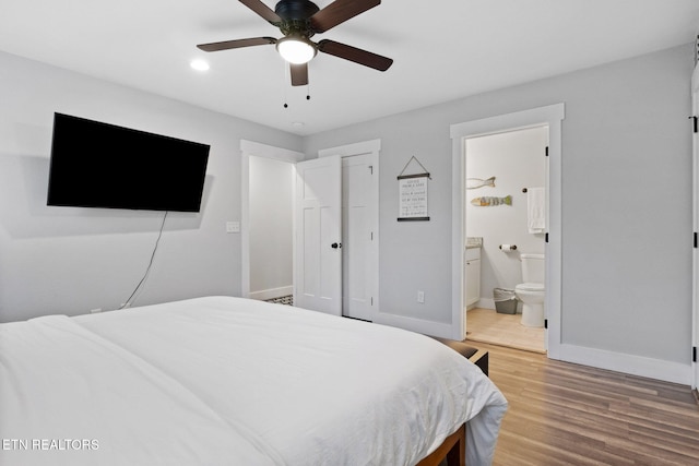 bedroom with hardwood / wood-style flooring, connected bathroom, ceiling fan, and a closet