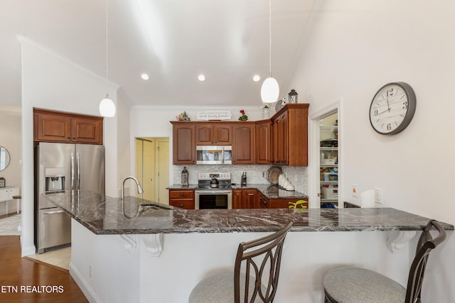 kitchen featuring sink, dark stone countertops, appliances with stainless steel finishes, pendant lighting, and decorative backsplash