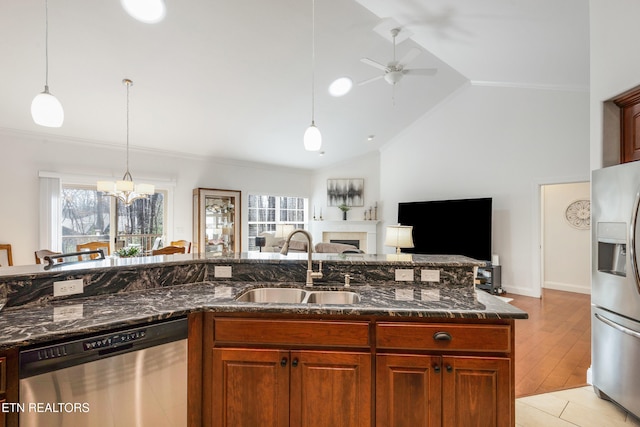 kitchen featuring appliances with stainless steel finishes, decorative light fixtures, sink, dark stone countertops, and crown molding