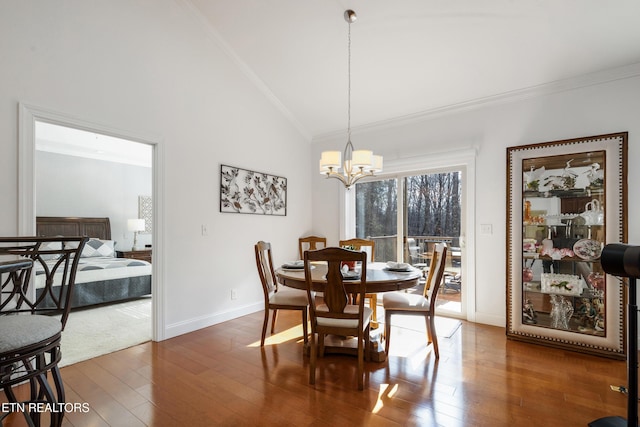 dining room with ornamental molding, dark wood-type flooring, a notable chandelier, and high vaulted ceiling