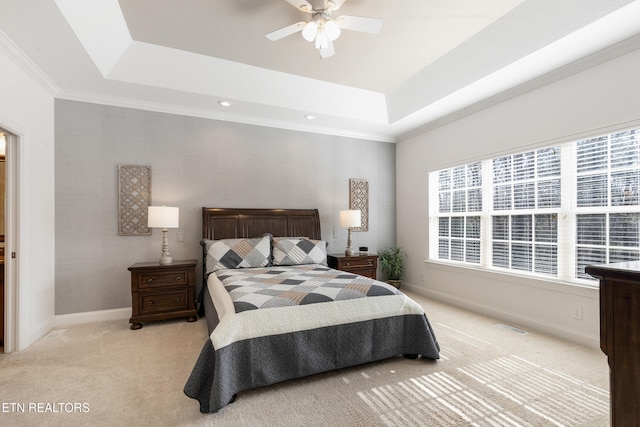 carpeted bedroom with a raised ceiling, crown molding, and ceiling fan