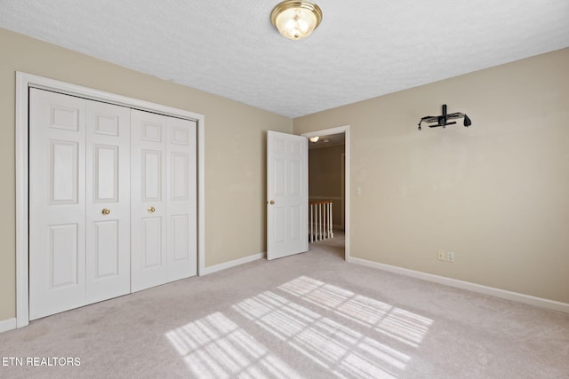 unfurnished bedroom with light carpet, a closet, and a textured ceiling