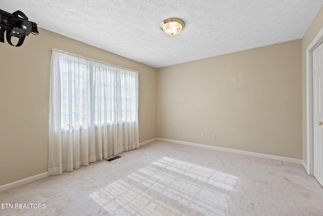 unfurnished room with light colored carpet and a textured ceiling