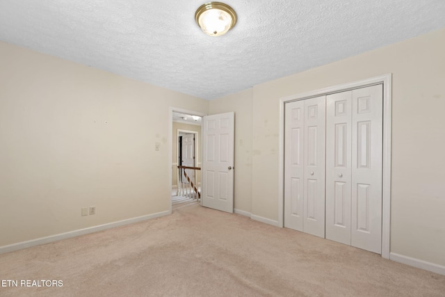 unfurnished bedroom with light carpet, a textured ceiling, and a closet