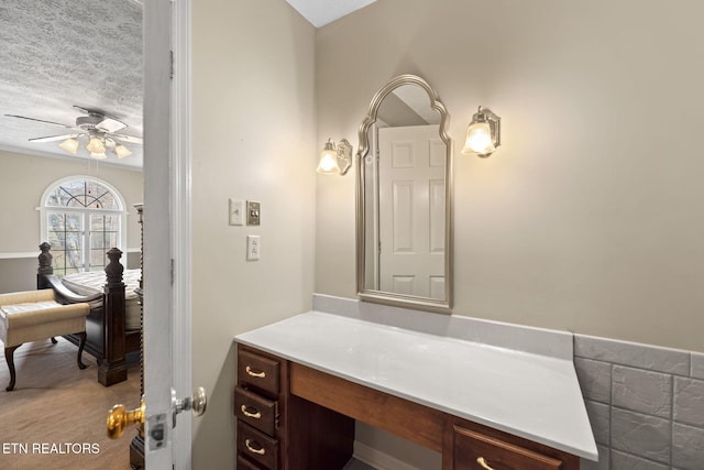 bathroom with ceiling fan, vanity, and a textured ceiling