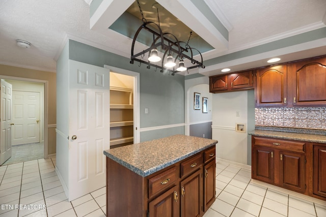 kitchen featuring light tile patterned floors, ornamental molding, a textured ceiling, a kitchen island, and decorative backsplash