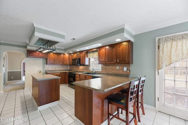 kitchen featuring sink, light tile patterned floors, electric range, kitchen peninsula, and a kitchen island