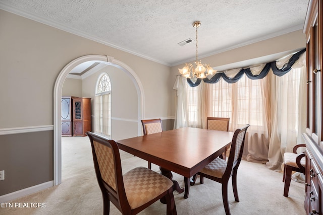 dining area featuring an inviting chandelier, crown molding, light carpet, and a textured ceiling