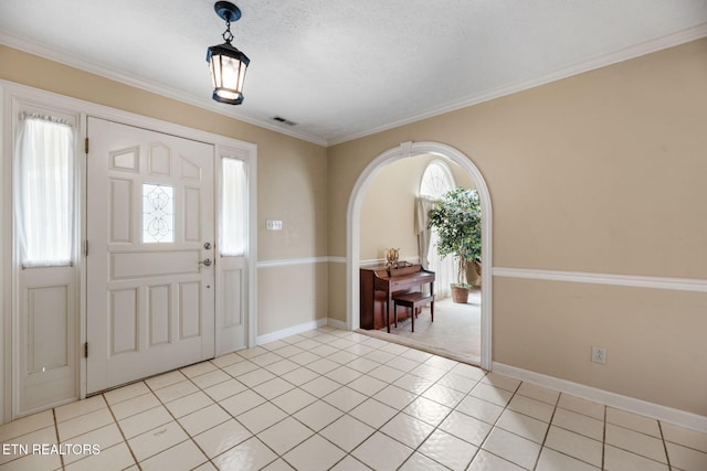 entrance foyer featuring ornamental molding, a textured ceiling, and light tile patterned flooring