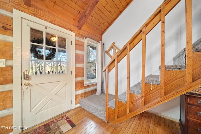 entryway with wood ceiling, vaulted ceiling with beams, light wood-type flooring, and wood walls