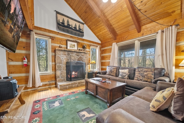 living room with a stone fireplace, a healthy amount of sunlight, hardwood / wood-style floors, and wooden walls