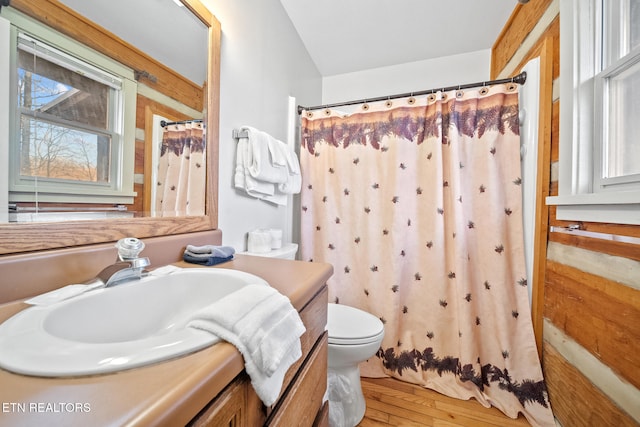 bathroom with hardwood / wood-style floors, vanity, a shower with curtain, vaulted ceiling, and toilet