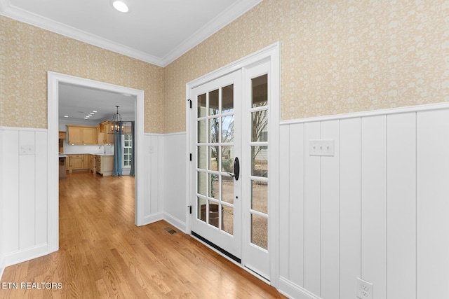 doorway to outside with crown molding, french doors, and light wood-type flooring