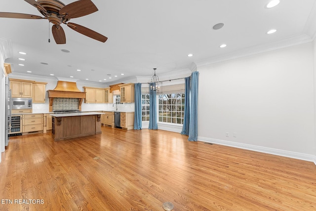 unfurnished living room featuring crown molding, sink, ceiling fan with notable chandelier, and light hardwood / wood-style flooring