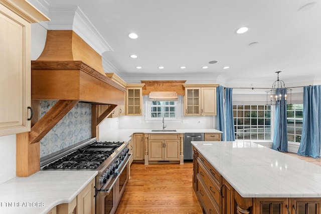 kitchen featuring appliances with stainless steel finishes, decorative light fixtures, sink, light stone counters, and light hardwood / wood-style flooring