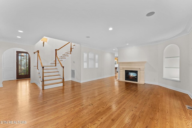 unfurnished living room featuring crown molding, built in shelves, and light hardwood / wood-style floors