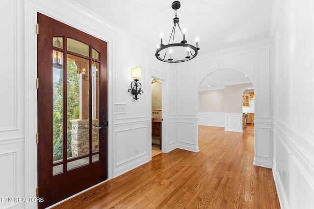 entryway featuring an inviting chandelier, crown molding, and light hardwood / wood-style floors