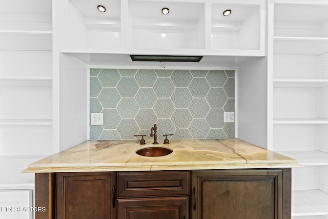 interior space featuring dark brown cabinetry, sink, and backsplash