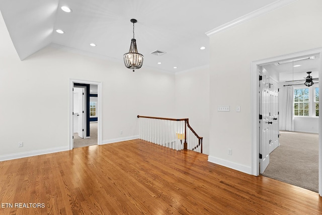 empty room with an inviting chandelier, lofted ceiling, ornamental molding, and light hardwood / wood-style floors