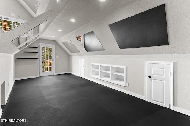 additional living space featuring built in features, vaulted ceiling, and a textured ceiling