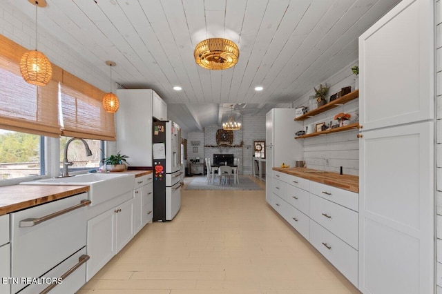 kitchen with hanging light fixtures, sink, white cabinets, and white appliances