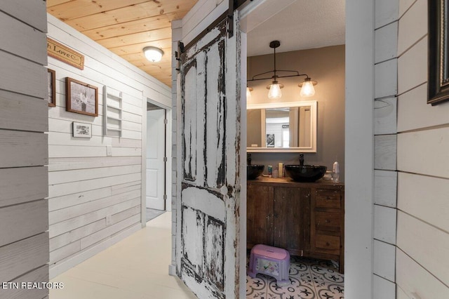 bathroom with wooden ceiling, vanity, and wood walls