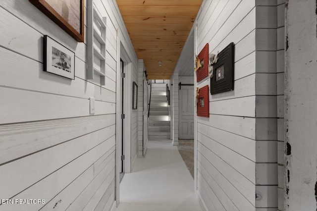 hallway featuring wooden ceiling and wood walls