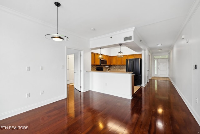 kitchen featuring black fridge, tasteful backsplash, crown molding, hanging light fixtures, and kitchen peninsula