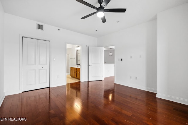 unfurnished bedroom featuring hardwood / wood-style flooring, connected bathroom, ceiling fan, and a closet