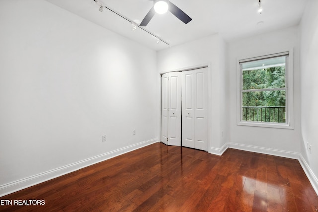 unfurnished bedroom with ceiling fan, dark hardwood / wood-style floors, track lighting, and a closet