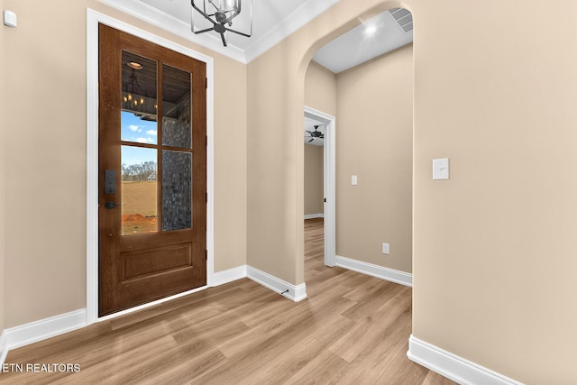 foyer with crown molding, an inviting chandelier, and light hardwood / wood-style flooring