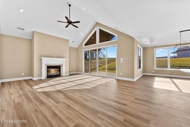 unfurnished living room featuring ceiling fan, high vaulted ceiling, a healthy amount of sunlight, and light hardwood / wood-style floors