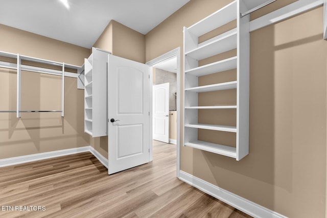 walk in closet with light hardwood / wood-style floors